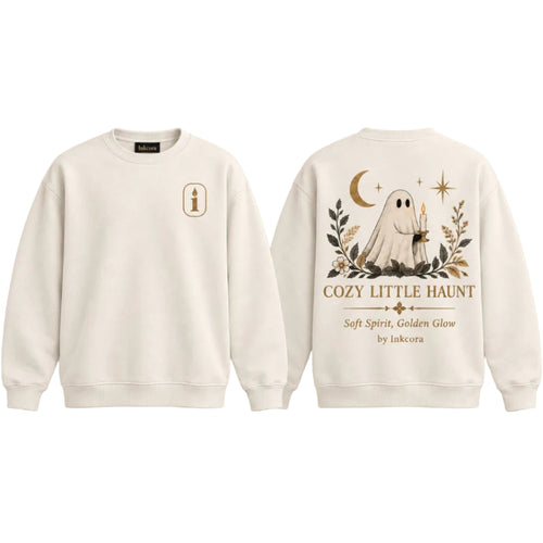 Crewneck sweatshirt with small Inkcora candle emblem on the front chest and large Cozy Little Haunt ghost graphic on the back in gold, cream, and dark neutral tones.